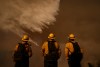 Firefighters watch water drops on the Palisades Fire in Mandeville Canyon Saturday, Jan. 11, 2025, in Los Angeles. (AP Photo/Eric Thayer)