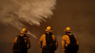 Firefighters watch water drops on the Palisades Fire in Mandeville Canyon Saturday, Jan. 11, 2025, in Los Angeles. (AP Photo/Eric Thayer)