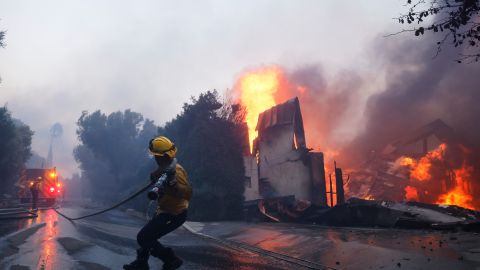 A firefighter battles the advancing Palisades Fire as it burns a structure in the Pacific Palisades neighborhood of Los Angeles, Tuesday, Jan. 7, 2025. (AP Photo/Etienne Laurent)