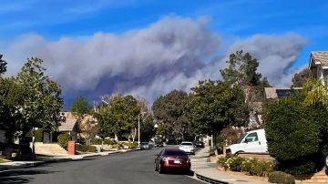 A large plume of smoke caused by the Hughes Fire rises from Castaic Lake as seen from a neighborhood of Santa Clarita, Calif., Wednesday, Jan. 22, 2025. (AP Photo/Marcio Jose Sanchez)