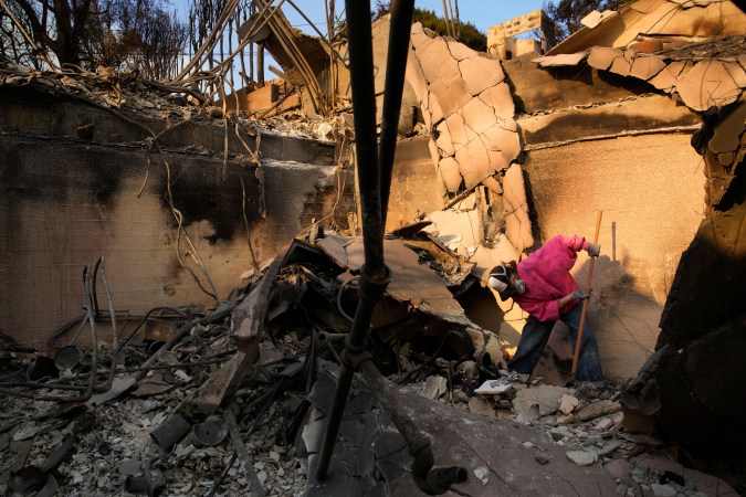 Kaegan Baron sifts through the rubble of her mother's home after it was destroyed by the Palisades Fire in the Pacific Palisades neighborhood of Los Angeles, Saturday, Jan. 11, 2025. (AP Photo/John Locher)