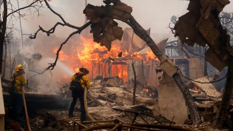 Firefighters battle the Palisades Fire as it burns a structure in the Pacific Palisades neighborhood of Los Angeles, Wednesday, Jan. 8, 2025. (AP Photo/Etienne Laurent)