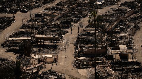Firefighters walk along a road in a fire-ravaged community in the aftermath of the Palisades Fire in the Pacific Palisades neighborhood of Los Angeles, Monday, Jan. 13, 2025. (AP Photo/John Locher)