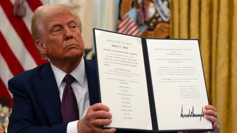 President Donald Trump holds up a signed executive order relating to clemency for anti-abortion protesters as he signs executive orders in the Oval Office of the White House, Thursday, Jan. 23, 2025, in Washington. (AP Photo/Ben Curtis)