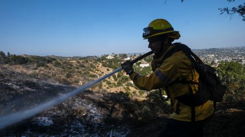 A firefighter sprays water on hot spots during a brushfire near the Griffith Observatory in the hills of Los Feliz in Los Angeles on Tuesday, May 17, 2022. (AP Photo/Ringo H.W. Chiu)