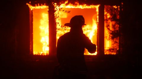 Un bombero intenta apagar las llamas mientras el incendio Palisades arrasa el vecindario Pacific Palisades de Los Ángeles.