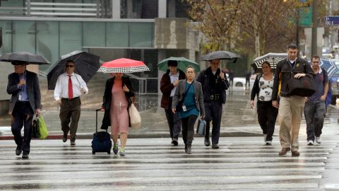 Commuters walk under a light rain downtown in Los Angeles on Wednesday, Feb. 17, 2016, as a storm system arriving in California ends days of clear skies, blazing sunshine and record-setting heat. The National Weather Service said the storm would arrive in Southern California by night, bringing gusty winds to the mountains and passes along with rain and snow through Thursday morning. (AP Photo/Nick Ut)