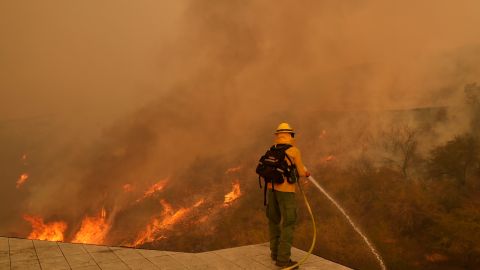 FILE - A firefighter hoses down flames as the Palisades Fire approaches in Mandeville Canyon, Jan. 11, 2025, in Los Angeles. (AP Photo/Jae C. Hong)