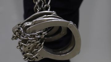 A prison guard holds handcuffs during a media tour of The Terrorism Confinement Center in Tecoluca, El Salvador, Thursday, Feb. 2, 2023. The "mega-prison" still under construction has a maximum capacity of 40,000 and is intended to imprison gang members, according to the government. (AP Photo/Salvador Melendez)