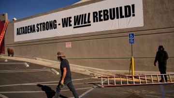 Rene Amy, left, and Sean Courtney pack up their stuff after hanging an "Altadena Strong" sign Wednesday, Jan. 15, 2025, in Altadena, Calif. (AP Photo/John Locher)