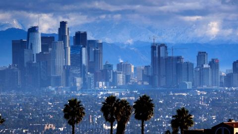 Heavy storm clouds and a dusting of snow are seen in the San Gabriel mountain range behind downtown Los Angeles on Friday, Nov. 29, 2019. California is drenched or blanketed in snow after a powerful Thanksgiving storm. Rain and snow showers are continuing in parts of the state Friday morning while skies are clearing elsewhere.(AP Photo/Richard Vogel)