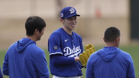 Los Angeles Dodgers pitcher Roki Sasaki, of Japan, smiles as he waits to warm up at the Dodgers baseball spring training facility, Wednesday, Feb. 12, 2025, in Phoenix. (AP Photo/Ross D. Franklin)