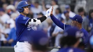 Los Angeles Dodgers designated hitter Shohei Ohtani high-fives manager Dave Roberts after hitting a home run during the first inning of a spring training baseball game Los Angeles Angels, Friday, Feb. 28, 2025, in Phoenix. (AP Photo/Ashley Landis)