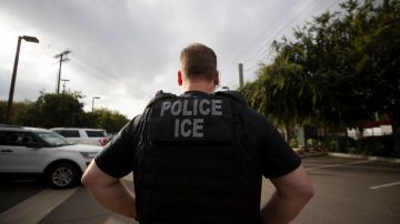 FILE - In this July 8, 2019, file photo, a U.S. Immigration and Customs Enforcement (ICE) officer looks on during an operation in Escondido, Calif. Advocacy groups and unions are pressuring Marriott, MGM and others not to house migrants who have been arrested by U.S. Immigration and Customs Enforcement agents. But the U.S. government says it sometimes needs bed space, and if hotels don’t help it might have to split up families. (AP Photo/Gregory Bull, File)