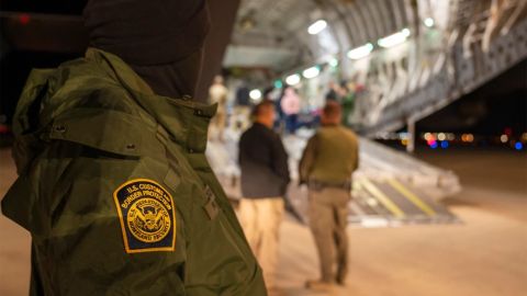 This photo provided by the U.S. Dept. of Defense, A U.S. Customs and Border Protection agent watches as undocumented immigrants are loaded onto a C-17 Globemaster III at Tucson International Airport in Tucson, Ariz., Thursday, Jan. 23, 2025. (Senior Airman Devlin Bishop/Dept. of Defense via AP)