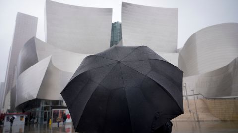 A pedestrian walks in front of the Walt Disney Concert Hall during a rain storm Wednesday, Feb. 5, 2025, in Los Angeles. (AP Photo/Damian Dovarganes)