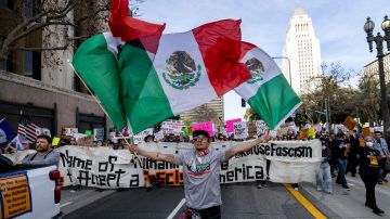 A demonstrator waves Mexican flags as they march during a rally to protest President Trump politics on Presidents Day Monday, Feb. 17, 2025, in Los Angeles. (AP Photo/Etienne Laurent)