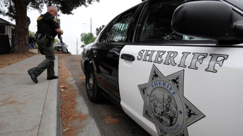 This Aug. 11, 2011 photo shows a San Diego county sheriff's deputy walking back to his car after serving a warrant at at a home in Fallbrook, Calif. State, federal and county officers served warrants in San Diego county on people suspected of smuggling drugs illegally into Mexico from the U.S. Authorities speculate that it was easier for smugglers to unload large batches of pills at those loosely regulated pharmacies than to distribute them in small amounts through American street dealers. (AP Photo/Denis Poroy)