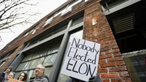 Personas protestan contra el rol de Elon Musk en el gobierno de Trump frente a una tienda de Tesla en Seattle.