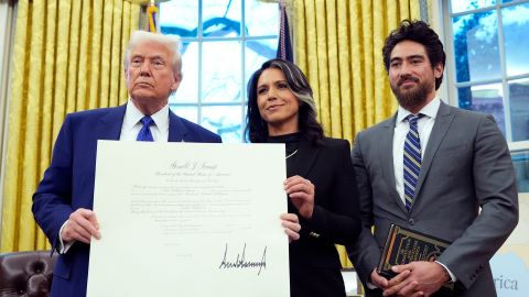 El presidente Donald Trump sostiene el documento de la comisión de la directora de Inteligencia Nacional, Tulsi Gabbard.