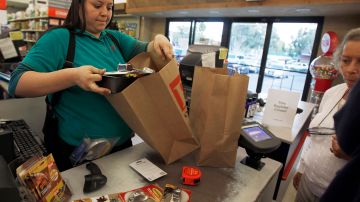 Cashier Denise Cruz checks out customers' purchases at a hardware store in Los Angeles Tuesday, Oct. 4, 2011. Service firms that employ 90 percent of the U.S. work force grew at a slower pace in September, evidence that the economy is growing but at a sluggish pace. (AP Photo/Reed Saxon)