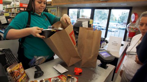 Cashier Denise Cruz checks out customers' purchases at a hardware store in Los Angeles Tuesday, Oct. 4, 2011. Service firms that employ 90 percent of the U.S. work force grew at a slower pace in September, evidence that the economy is growing but at a sluggish pace. (AP Photo/Reed Saxon)