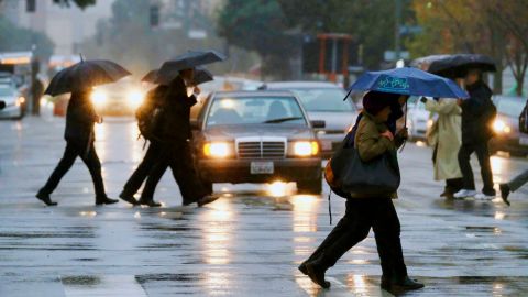 Downtown workers make their way along a soggy street in downtown Los Angeles on Thursday, Jan. 12, 2107. Flooded roads and freeways along with low fog and clouds made for a hazardous commute Thursday as another round of heavy rain moved through Southern California, raising fresh fears of possible mudslides in wildfire burn areas. (AP Photo/Richard Vogel)