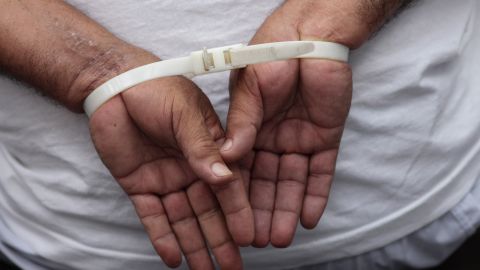 FILE - A handcuffed man, arrested for alleged gang connections, waits to be transferred to a prison at the police delegation of San Bartolo in Soyapango, El Salvador, Aug. 16, 2022. Congress voted on Dec. 14 to extend President Nayib Bukele’s emergency powers to crack down on gangs for the ninth time. (AP Photo/Salvador Melendez, File)