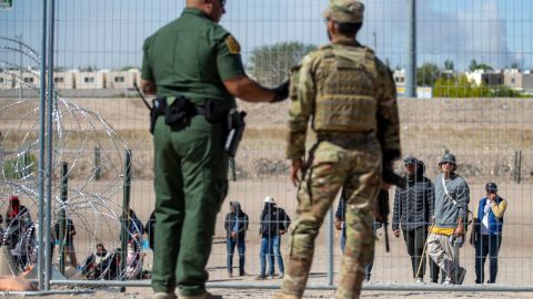 Migrantes aguardan a un costado del muro fronterizo vigilado por la Patrulla Fronteriza y la Guardia Nacional de Texas el miércoles 10 de mayo de 2023, con el fin de ingresar a El Paso, Texas. A partir del jueves, el gobierno del presidente Joe Biden comenzará a negarle el asilo a los migrantes que se presenten en la frontera con México sin primero haber presentado una solicitud en línea o pedido protección en el país por el que pasaron, según una nueva medida dada a conocer el miércoles. Las autoridades federales han advertido de complicaciones en los próximos días en un momento en que expira la medida conocida como Título 42, la cual permitía expulsar rápidamente a migrantes para prevenir la propagación del COVID-19. (AP Foto/Andrés Leighton)