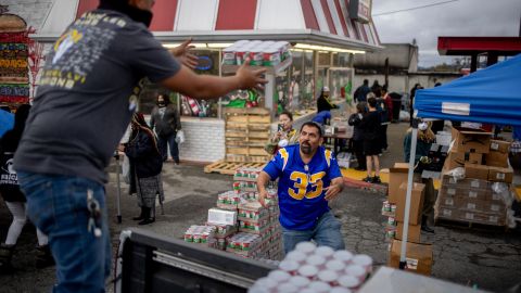 A person tosses a package of food to load onto a truck provided by World Central Kitchen at the site of the Eaton Fire, Thursday, Feb. 6, 2025, in Altadena, Calif. (AP Photo/Ethan Swope)