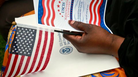 Fatoumata Jangana, from Gambia, holds a program and flag during U.S. Citizen and Immigration Services (USCIS) ceremony for fifty new citizens from twenty four countries, Friday June 16, 2017, in New York. Jangana became a citizen after 21 years in the U.S. (AP Photo/Bebeto Matthews)