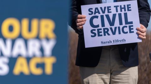 Un trabajador federal en período de prueba despedido sostiene un cartel que dice "Salvemos el servicio civil" en un evento en Washington D.C.