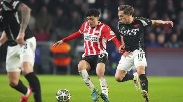 PSV's Richard Ledezma, left, challenges for the ball with Arsenal's Leandro Trossard during the Champions League, round of 16, first leg soccer match between PSV and Arsenal at the Phillips Stadium in Eindhoven, Netherlands, Tuesday, March 4, 2025. (AP Photo/Peter Dejong)