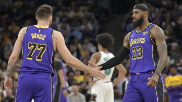 Los Angeles Lakers guard Luka Doncic (77) and forward LeBron James (23) greet each other on the court in the first half of an NBA basketball game against the Memphis Grizzlies, Saturday, March 29, 2025, in Memphis, Tenn. (AP Photo/Brandon Dill)
