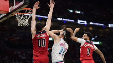 Miami Heat guard Jaime Jaquez Jr. (11) shoots in between Washington Wizards forwards Tristan Vukcevic (00) and Justin Champagnie (9) during the second half of a basketball game, Sunday, April 13, 2025, in Miami. (AP Photo/Michael Laughlin)