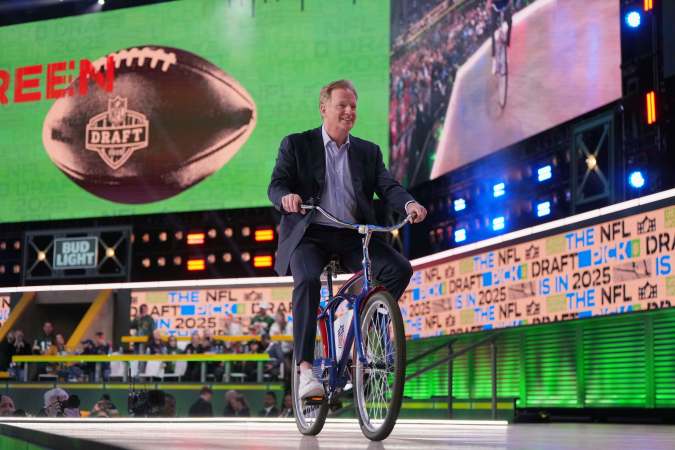 Roger Goodell, comisionado de la NFL, llega al escenario del Draft 2025 conduciendo una bicicleta frente a una masiva asistencia de fans afuera del estadio Lambeau Field de Green Bay.