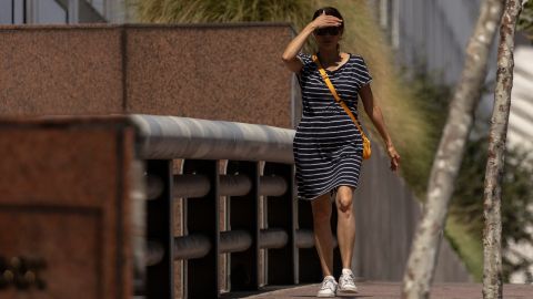 A woman shields her eyes from the sun as she walks in downtown Los Angeles during a heatwave Friday, Sept. 6, 2024. (AP Photo/Etienne Laurent)