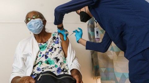Nursing student Andrew Wong, right, vaccinates South Los Angeles resident Annie Carmichael with her first dose of the Pfizer COVID-19 vaccine to prevent the coronavirus at the MLK Community Medical Group clinic in Los Angeles, Wednesday, Feb. 24, 2021. Eligible residents of South Los Angeles can get free vaccines at a series of vaccine clinics run by MLKCH. Current eligibility is limited for community members, including healthcare workers in Phase 1A and persons 65 years and older, that reside in Service Planning Area 6 of Los Angeles while supplies last. (AP Photo/Damian Dovarganes)