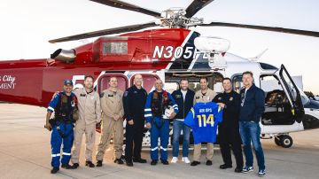 El entrenador en jefe Sean McVay y el gerente general Les Snead posan con personal del Departamento de Bomberos de Los Ángeles en las instalaciones de Operaciones Aéreas del LAFD.