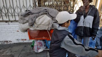 Julie, right, a homeless woman who would not reveal her last name, smokes a cigarette while guarding her belongings where she spent the night on the sidewalk as pedestrians pass Wednesday, Dec. 1, 2004, in Los Angeles. "It was really cold out here last night but the key is having lots of blankets, " Julie said. Unseasonably cold weather has hit the state this week straining homeless shelters' capacities and threatening the state's agriculture crops. (AP Photo/Ric Francis)