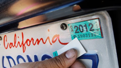 A woman puts new registration sticker on her car at a Department of Motor Vehicles office in Redwood City, Calif., Thursday, June 30, 2011. All Californians with a vehicle will pay $12 more a year to register it and millions of property owners who live outside cities will pay $150 a year for state fire protection. Those are among the new fees included in the state budget passed late Tuesday night without any Republican support. (AP Photo/Paul Sakuma)