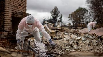 Volunteers from Samaritan's Purse help search a home for items that survived the Eaton Fire, Thursday, Feb. 6, 2025, in Altadena, Calif. (AP Photo/Ethan Swope)