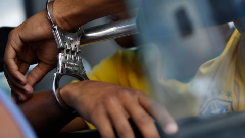 A handcuffed suspect waits inside a police bus during an operation against alleged drug traffickers at the Complexo do Alemao slum in Rio de Janeiro, Brazil, Saturday, Nov. 27, 2010. Soldiers and police crouching behind armored vehicles trained their rifles on dozens of entrances to a sprawling slum Saturday, preparing to invade and try to push drug gangs out an area long considered the most dangerous in Rio de Janeiro, a city set to host the 2016 Olympics. (AP Photo/Felipe Dana)