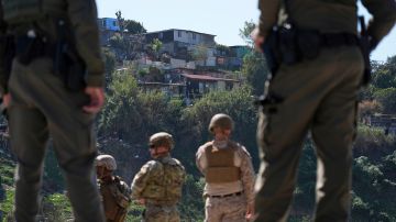 Agentes de CBP y militares observan Tijuana desde la frontera de EE.UU. con México en San Diego.