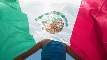 Kimberly Esparza walks draped in a Mexican flag during a protest against presidential candidate Donald Trump, Thursday, July 23, 2015, at Laredo International Airport in Laredo, Texas. (AP Photo/Darren Abate)