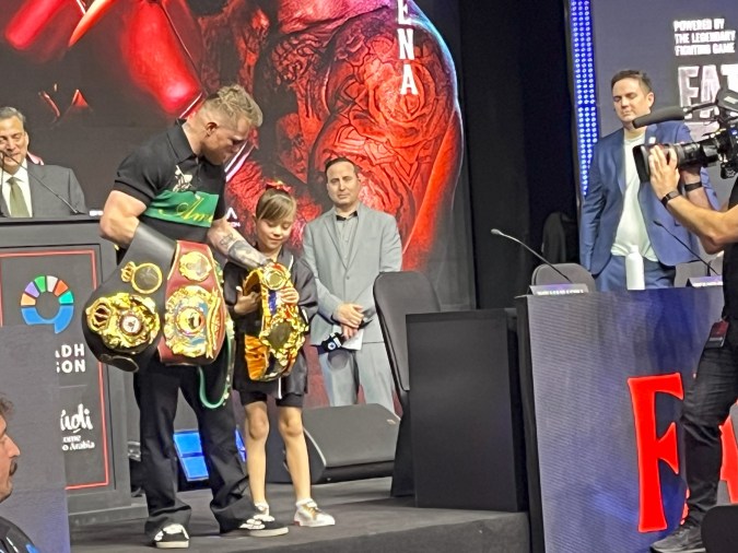 María Fernanda, hija de Canelo Álvarez, le ayuda a cargar sus cinturones de campeón mundial durante la conferencia de prensa en Riad, Arabia Saudita, donde el mexicano se enfrentará a William Scull.