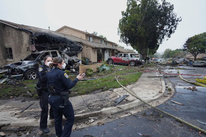 Authorities work the scene where a small plane crashed into a San Diego neighborhood, setting several homes on fire and forcing evacuations along several blocks early Thursday, May 22, 2025. (AP Photo/Gregory Bull)