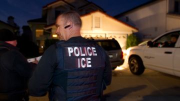 In this March 30, 2012 photo, an Immigration and Customs Enforcement (ICE) agent waits with other agents outside of the home of a suspect before dawn as part of a nationwide immigration sweep in San Diego. Federal officials say they arrested more than 3,100 immigrants convicted of serious crimes and fugitives in a six-day nationwide sweep. Officials at U.S. Immigration and Customs Enforcement say the sweep included every state and involved more than 1,900 of the agencys officers and agents. (AP Photo/Gregory Bull)