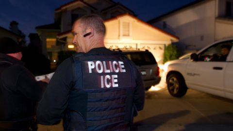 In this March 30, 2012 photo, an Immigration and Customs Enforcement (ICE) agent waits with other agents outside of the home of a suspect before dawn as part of a nationwide immigration sweep in San Diego. Federal officials say they arrested more than 3,100 immigrants convicted of serious crimes and fugitives in a six-day nationwide sweep. Officials at U.S. Immigration and Customs Enforcement say the sweep included every state and involved more than 1,900 of the agencys officers and agents. (AP Photo/Gregory Bull)