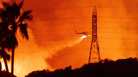FILE - A helicopter drops water on the Palisades Fire in Mandeville Canyon, Friday, Jan. 10, 2025, in Los Angeles. (AP Photo/Ethan Swope, File)
